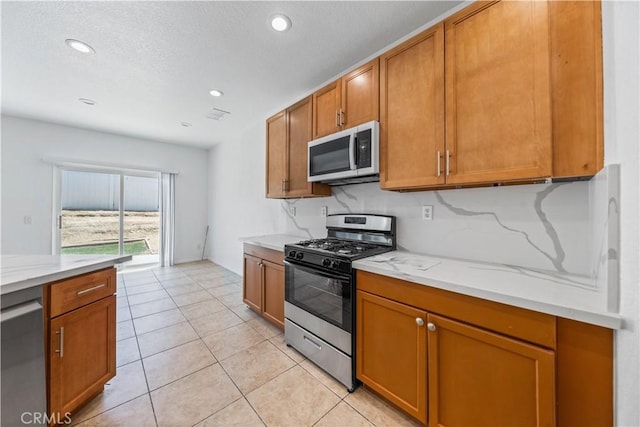 1568 Burns Ln, San Jacinto, CA 92335 - kitchen featuring appliances with stainless steel finishes, brown cabinets, recessed lighting, light tile patterned flooring, and a textured ceiling
