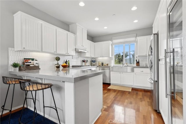 103 Corte Tierra Bella, San Clemente, CA 92673 - kitchen featuring a peninsula, appliances with stainless steel finishes, a sink, wood finished floors, and white cabinetry