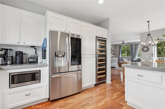 103 Corte Tierra Bella, San Clemente, CA 92673 - kitchen with appliances with stainless steel finishes, wine cooler, white cabinetry, light wood-type flooring, and a chandelier