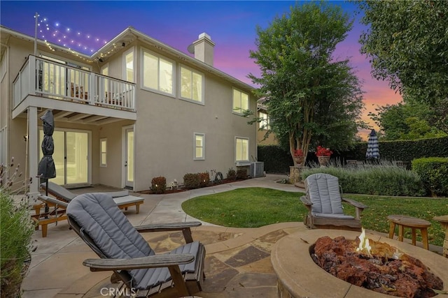 103 Corte Tierra Bella, San Clemente, CA 92673 - back of house at dusk featuring a balcony, a fire pit, a patio area, a chimney, and stucco siding