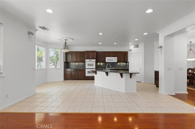 30185 Tenaya Ln, Highland, CA 92346 - kitchen with white appliances, a breakfast bar, light tile patterned flooring, crown molding, and tasteful backsplash