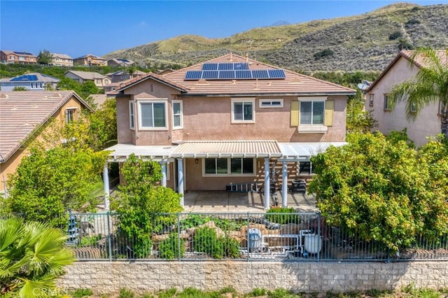 30185 Tenaya Ln, Highland, CA 92346 - rear view of property with stucco siding, solar panels, a fenced backyard, a mountain view, and a pergola