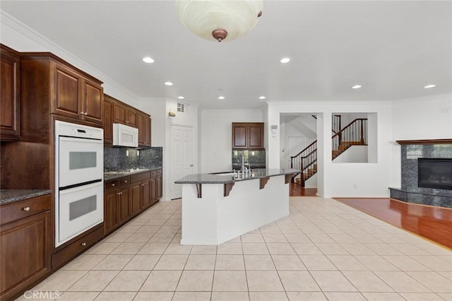 30185 Tenaya Ln, Highland, CA 92346 - kitchen with white appliances, a breakfast bar area, a sink, decorative backsplash, and crown molding