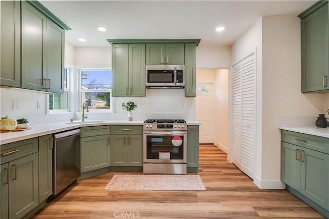 9331 Hunt Ave, South Gate, CA 90280 - kitchen with green cabinets, appliances with stainless steel finishes, a sink, light wood-style flooring, and light countertops