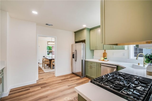9331 Hunt Ave, South Gate, CA 90280 - kitchen featuring green cabinets, appliances with stainless steel finishes, a sink, light countertops, and light wood-type flooring