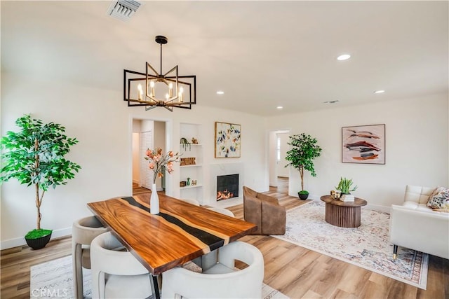 9331 Hunt Ave, South Gate, CA 90280 - dining room featuring wood finished floors, baseboards, a warm lit fireplace, recessed lighting, and a chandelier