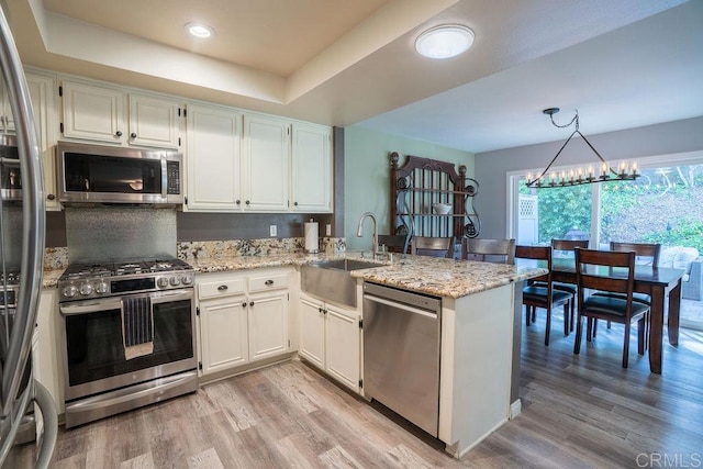 1302 El Corral Ln, San Marcos, CA 92078 - kitchen with appliances with stainless steel finishes, a peninsula, light wood-style floors, light stone counters, and white cabinets