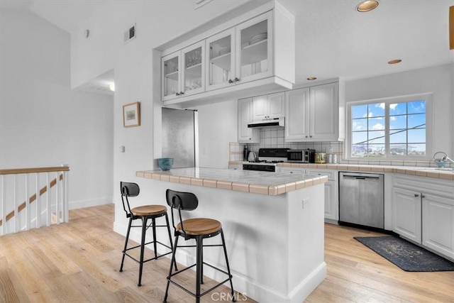 320 W 19th St Unit 1, San Pedro, CA 90731 - kitchen featuring appliances with stainless steel finishes, under cabinet range hood, tile countertops, light wood-style flooring, and recessed lighting
