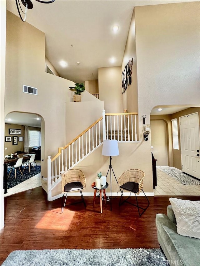 5890 Kendrick Dr, Riverside, CA 92507 - living room with arched walkways, wood-type flooring, stairs, healthy amount of natural light, and a towering ceiling