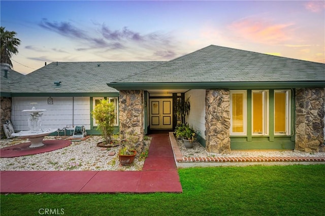 20043 Emerald Meadow Dr, Walnut, CA 91789 - exterior entry at dusk with stone siding, a yard, and roof with shingles