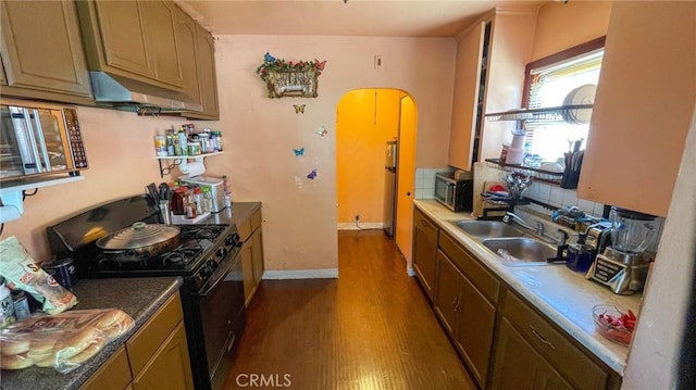8933 Bowman Ave, South Gate, CA 90280 - kitchen with black gas stove, stainless steel microwave, under cabinet range hood, dark wood-type flooring, and a sink