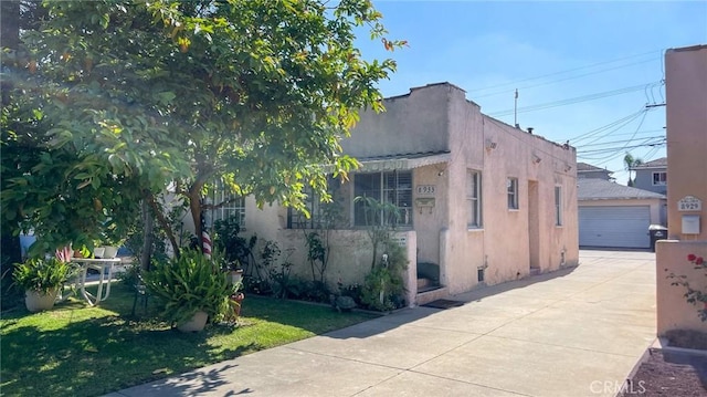 8933 Bowman Ave, South Gate, CA 90280 - view of side of property featuring stucco siding, a detached garage, an outdoor structure, and a lawn