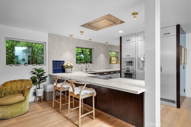 541 1st St, Manhattan Beach, CA 90266 - kitchen featuring a peninsula, light wood-type flooring, light countertops, a sink, and recessed lighting