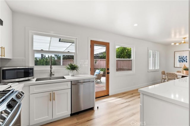 3145 Sicily Ave, Costa Mesa, CA 92626 - kitchen with appliances with stainless steel finishes, a sink, decorative backsplash, light wood-style floors, and light countertops