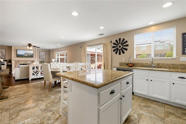 29304 Riptide Dr, Menifee, CA 92585 - kitchen featuring a sink, a kitchen island, white cabinetry, recessed lighting, and light stone countertops