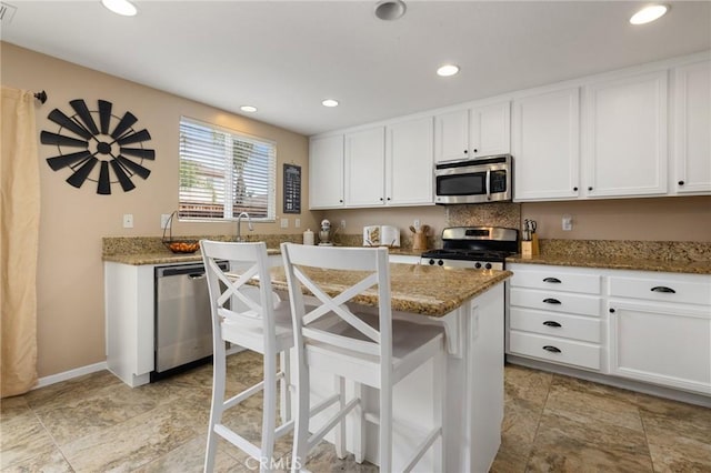 29304 Riptide Dr, Menifee, CA 92585 - kitchen with stainless steel appliances, white cabinetry, stone counters, a kitchen island, and recessed lighting