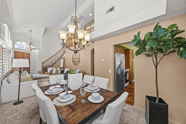 14252 Parkside Ct, Chino Hills, CA 91709 - dining space with a chandelier, light colored carpet, high vaulted ceiling, and stairs