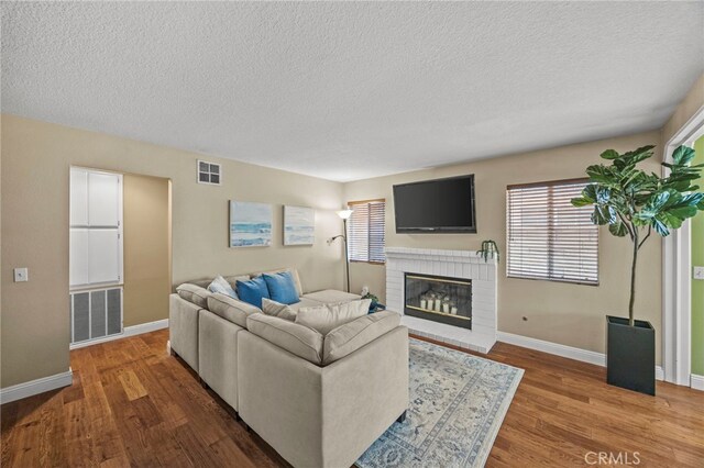 14252 Parkside Ct, Chino Hills, CA 91709 - living area with wood finished floors, a textured ceiling, a brick fireplace, and baseboards