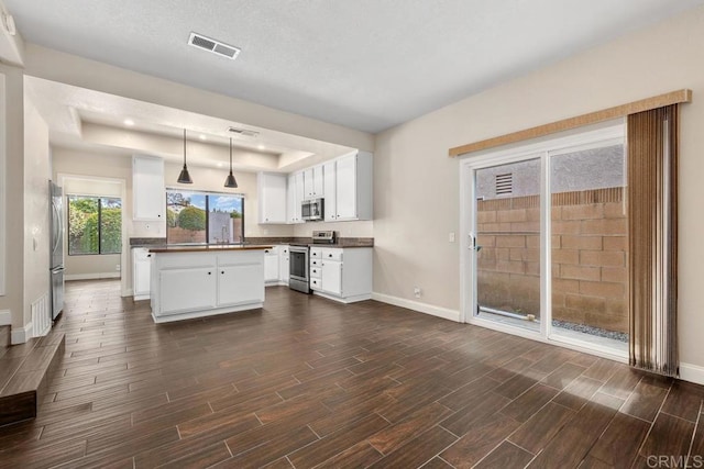 6 Cape Cod, Irvine, CA 92620 - kitchen featuring stainless steel appliances, a raised ceiling, dark countertops, and wood tiled floors