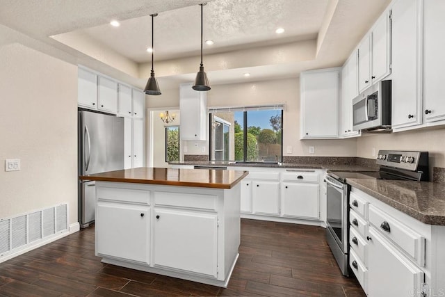 6 Cape Cod, Irvine, CA 92620 - kitchen featuring appliances with stainless steel finishes, a raised ceiling, a center island, white cabinetry, and dark wood-type flooring