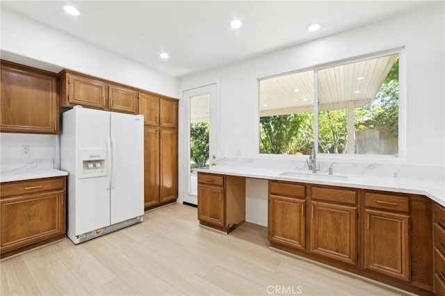 1172 Cedar Hollow Rd, Beaumont, CA 92223 - kitchen featuring white fridge with ice dispenser, brown cabinetry, light countertops, light wood-style floors, and recessed lighting