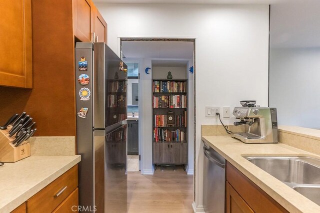 18350 Hatteras St Unit 169, Tarzana, CA 91356 - kitchen with appliances with stainless steel finishes, brown cabinets, light countertops, and light wood-type flooring