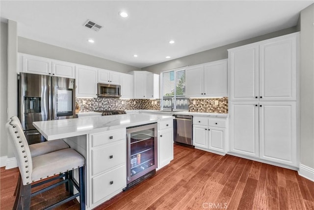 27697 Sonora Cir, Temecula, CA 92591 - kitchen with beverage cooler, stainless steel appliances, wood finished floors, backsplash, and recessed lighting