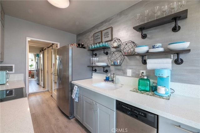 100 Atlantic Ave Unit 603, Long Beach, CA 90802 - kitchen with open shelves, stainless steel appliances, a sink, light wood finished floors, and light countertops