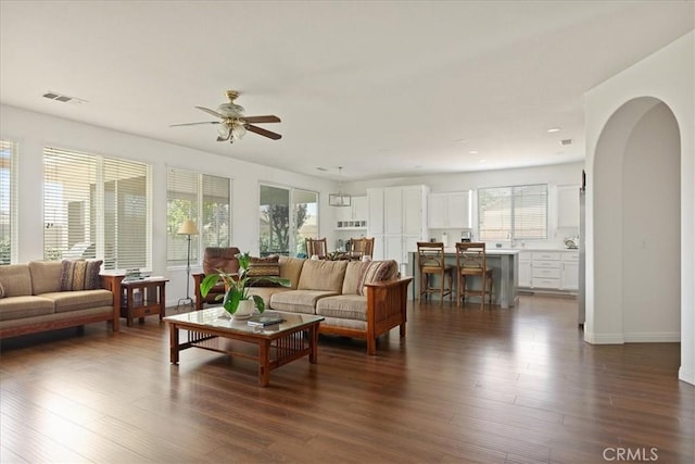 1467 Hunter Moon Way, Beaumont, CA 92223 - living room featuring a ceiling fan, dark wood-style floors, arched walkways, and baseboards