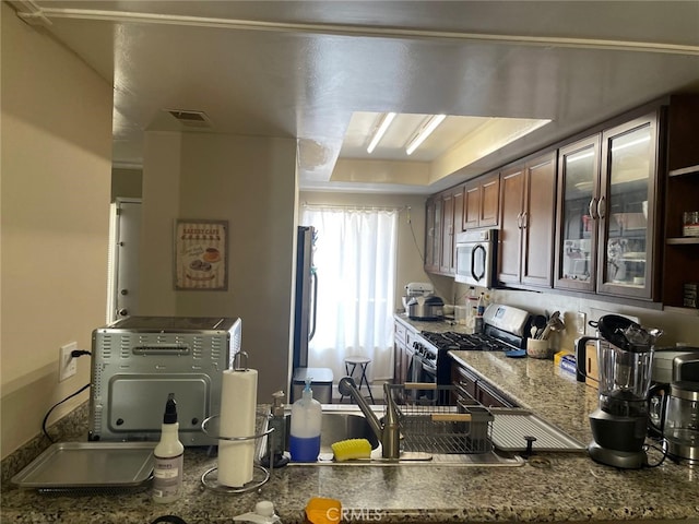 404 Brighton Spgs, Costa Mesa, CA 92627 - kitchen featuring appliances with stainless steel finishes, glass insert cabinets, a raised ceiling, and stone counters