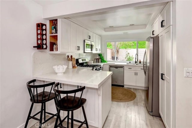 32457 Spyglass Ct, San Juan Capistrano, CA 92675 - kitchen with stainless steel appliances, a sink, a peninsula, a raised ceiling, and white cabinetry