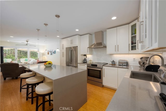 6017 Carnegie St, San Diego, CA 92122 - kitchen featuring stainless steel appliances, wall chimney range hood, a sink, light wood-style flooring, and recessed lighting