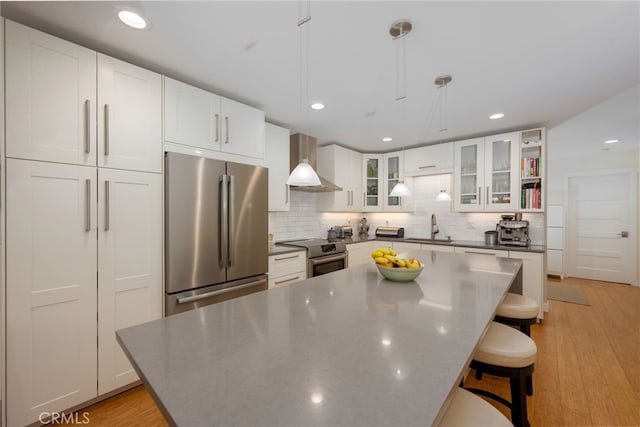 6017 Carnegie St, San Diego, CA 92122 - kitchen with appliances with stainless steel finishes, wall chimney exhaust hood, a sink, backsplash, and white cabinetry