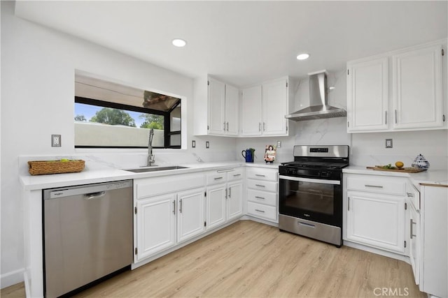 1348 Sandia St, Corona, CA 92882 - kitchen featuring appliances with stainless steel finishes, wall chimney exhaust hood, a sink, white cabinets, and light wood finished floors
