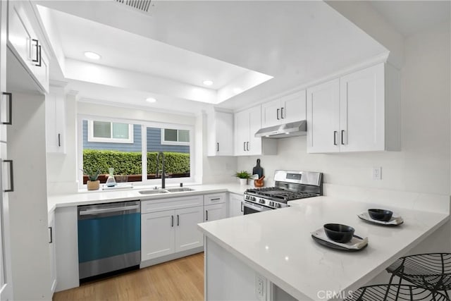 921 Boon Pl Unit A, Corona, CA 92881 - kitchen with dishwashing machine, stainless steel gas range oven, under cabinet range hood, a peninsula, and white cabinetry