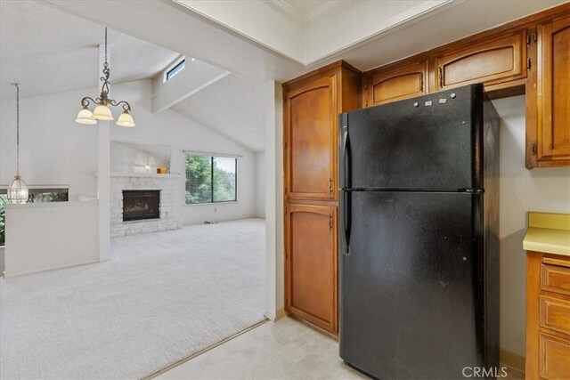 645 Worcester Dr, Cambria, CA 93428 - kitchen featuring freestanding refrigerator, brown cabinetry, pendant lighting, a fireplace, and a chandelier