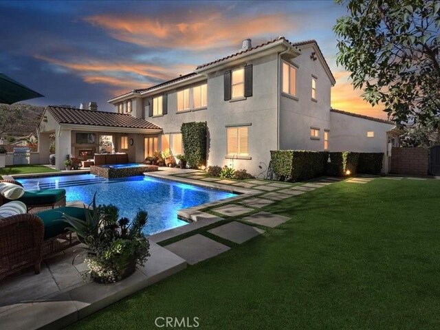 29310 Paseo Palmar, San Juan Capistrano, CA 92675 - back of property at dusk featuring stucco siding, a patio, and a pool with connected hot tub