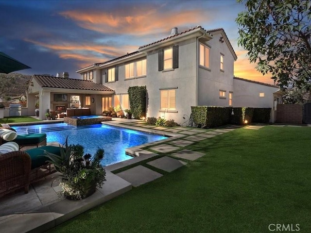 29310 Paseo Palmar, San Juan Capistrano, CA 92675 - back of house at dusk featuring stucco siding, a patio area, and a pool with connected hot tub