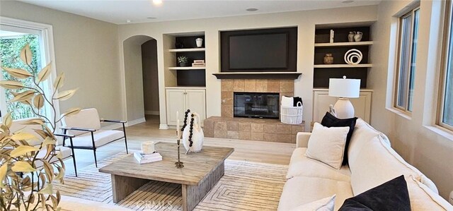 29310 Paseo Palmar, San Juan Capistrano, CA 92675 - living room featuring built in shelves, arched walkways, a tile fireplace, wood finished floors, and baseboards