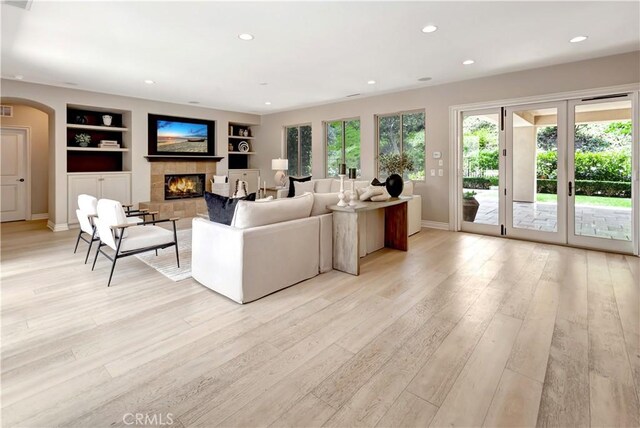 29310 Paseo Palmar, San Juan Capistrano, CA 92675 - living room with built in features, a lit fireplace, arched walkways, light wood-type flooring, and baseboards