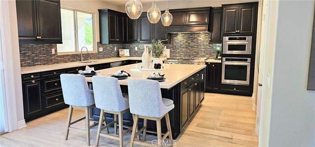 29310 Paseo Palmar, San Juan Capistrano, CA 92675 - kitchen with a breakfast bar, light wood-type flooring, decorative backsplash, and a sink
