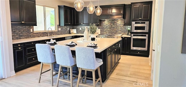 29310 Paseo Palmar, San Juan Capistrano, CA 92675 - kitchen featuring a breakfast bar, tasteful backsplash, light wood-type flooring, and dark cabinets