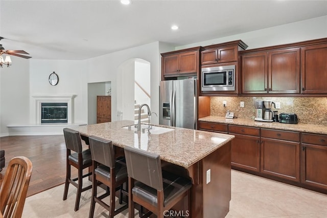 19728 Ellis Henry Ct, Newhall, CA 91321 - kitchen with appliances with stainless steel finishes, a sink, tasteful backsplash, a kitchen island with sink, and a breakfast bar