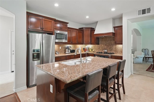 19728 Ellis Henry Ct, Newhall, CA 91321 - kitchen featuring appliances with stainless steel finishes, a sink, wall chimney range hood, light stone countertops, and arched walkways