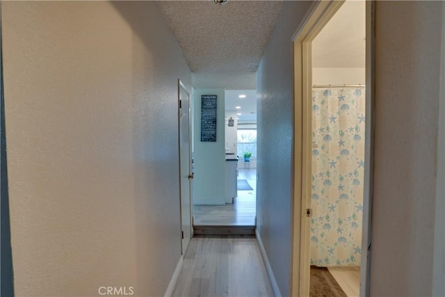 12076 Racket Ct, Moreno Valley, CA 92557 - corridor with light wood-style floors, baseboards, a textured wall, and a textured ceiling