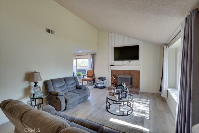 12076 Racket Ct, Moreno Valley, CA 92557 - living room featuring a fireplace, light wood finished floors, a textured ceiling, and high vaulted ceiling
