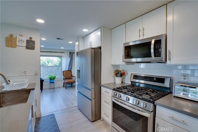 12076 Racket Ct, Moreno Valley, CA 92557 - kitchen with stainless steel appliances, light wood-style flooring, white cabinetry, decorative backsplash, and recessed lighting