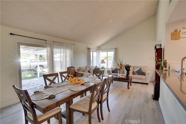 12076 Racket Ct, Moreno Valley, CA 92557 - dining area featuring vaulted ceiling, light wood-style flooring, and a textured ceiling