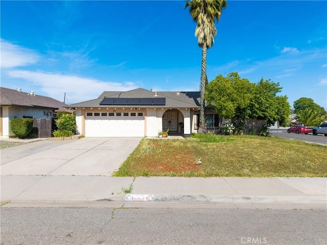 12076 Racket Ct, Moreno Valley, CA 92557 - ranch-style house with roof mounted solar panels, stucco siding, a front yard, and a garage