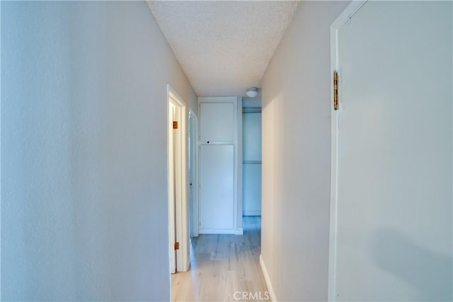 12076 Racket Ct, Moreno Valley, CA 92557 - hall featuring a textured ceiling, light wood-style floors, and baseboards